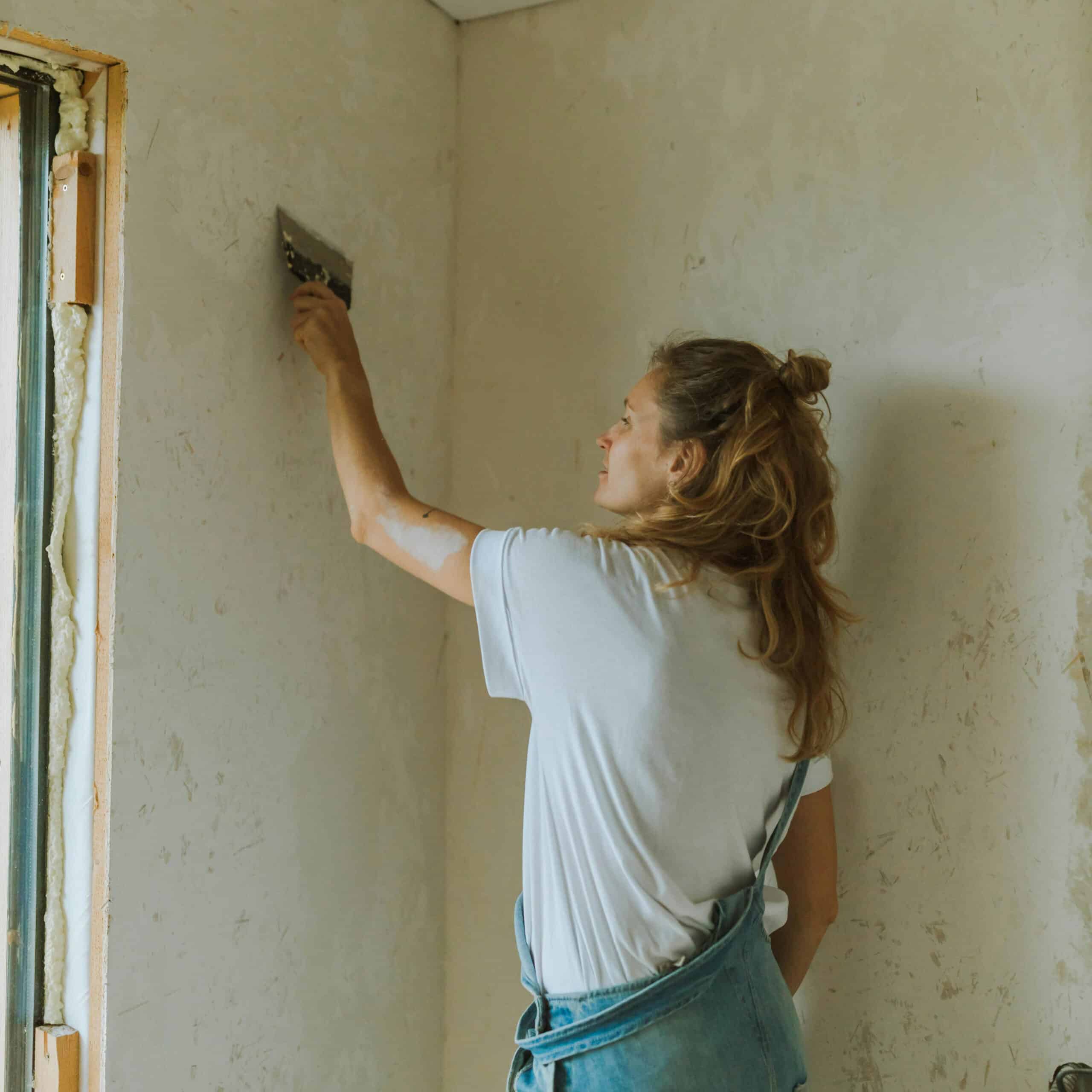 Rénover une maison soi-même - Un femme en train de préparer un mur avant de le peindre
