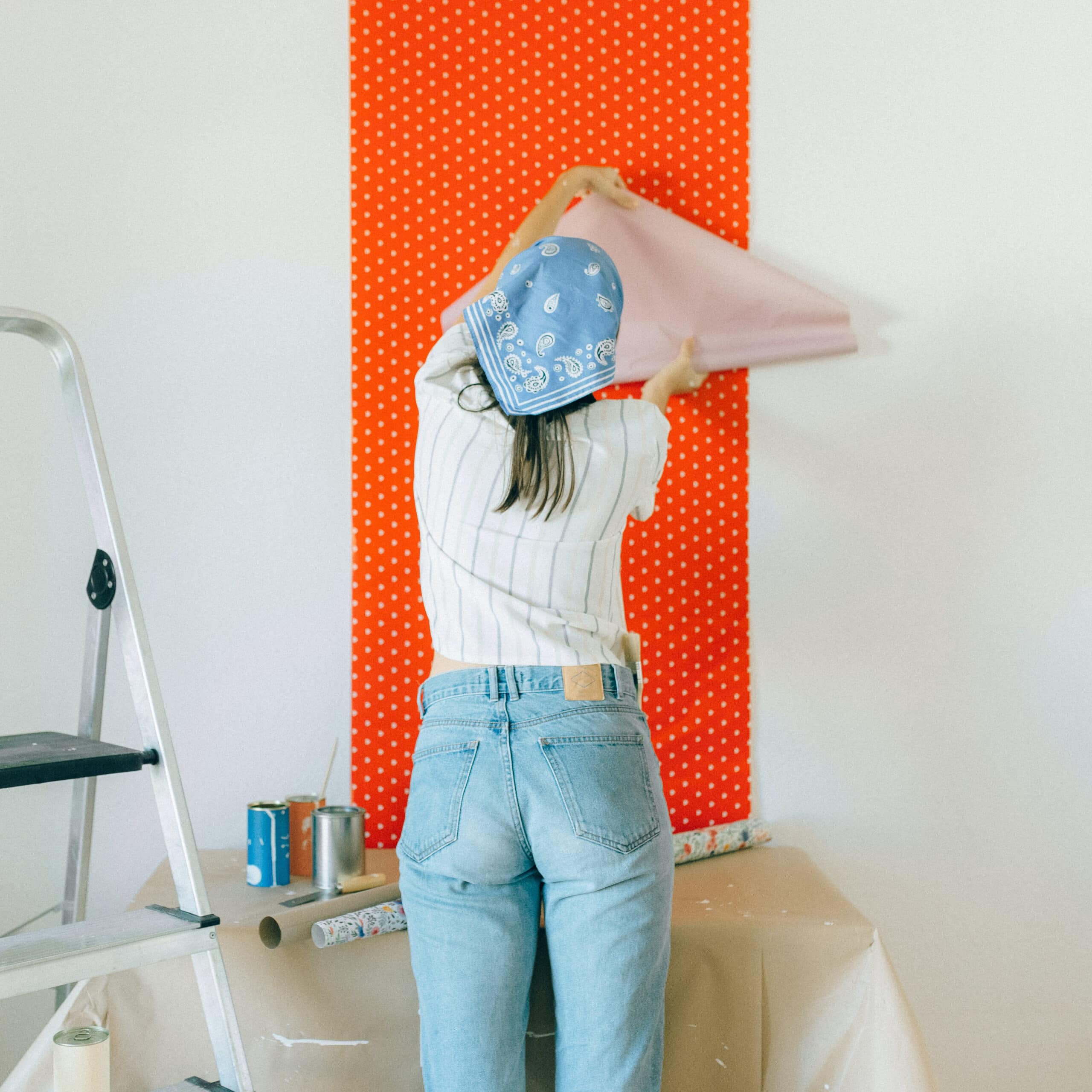 Rénover une maison soi-même - Une femme en train de poser du papier peint