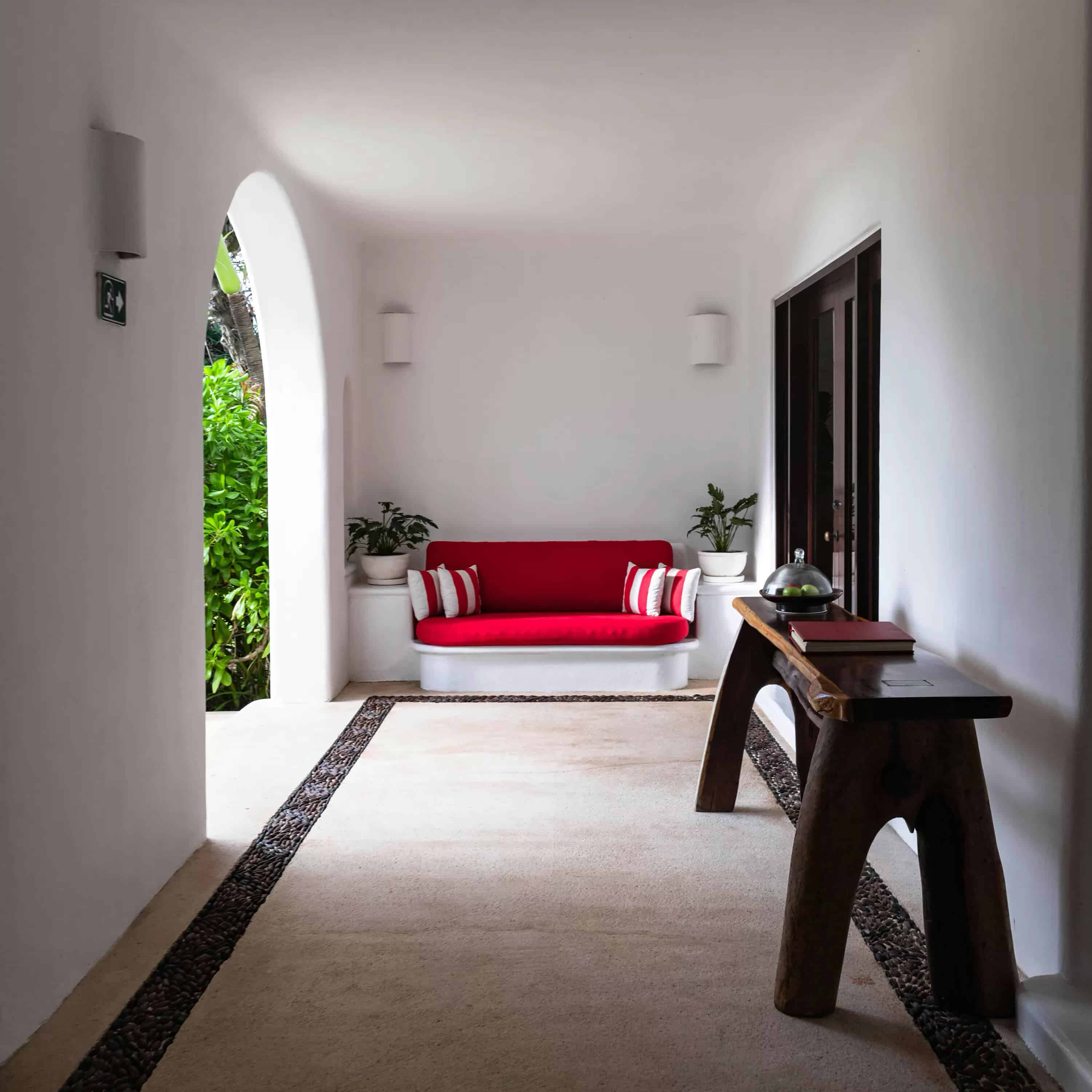 Comment décorer un couloir – un couloir large décoré avec une console et un sofa rouge