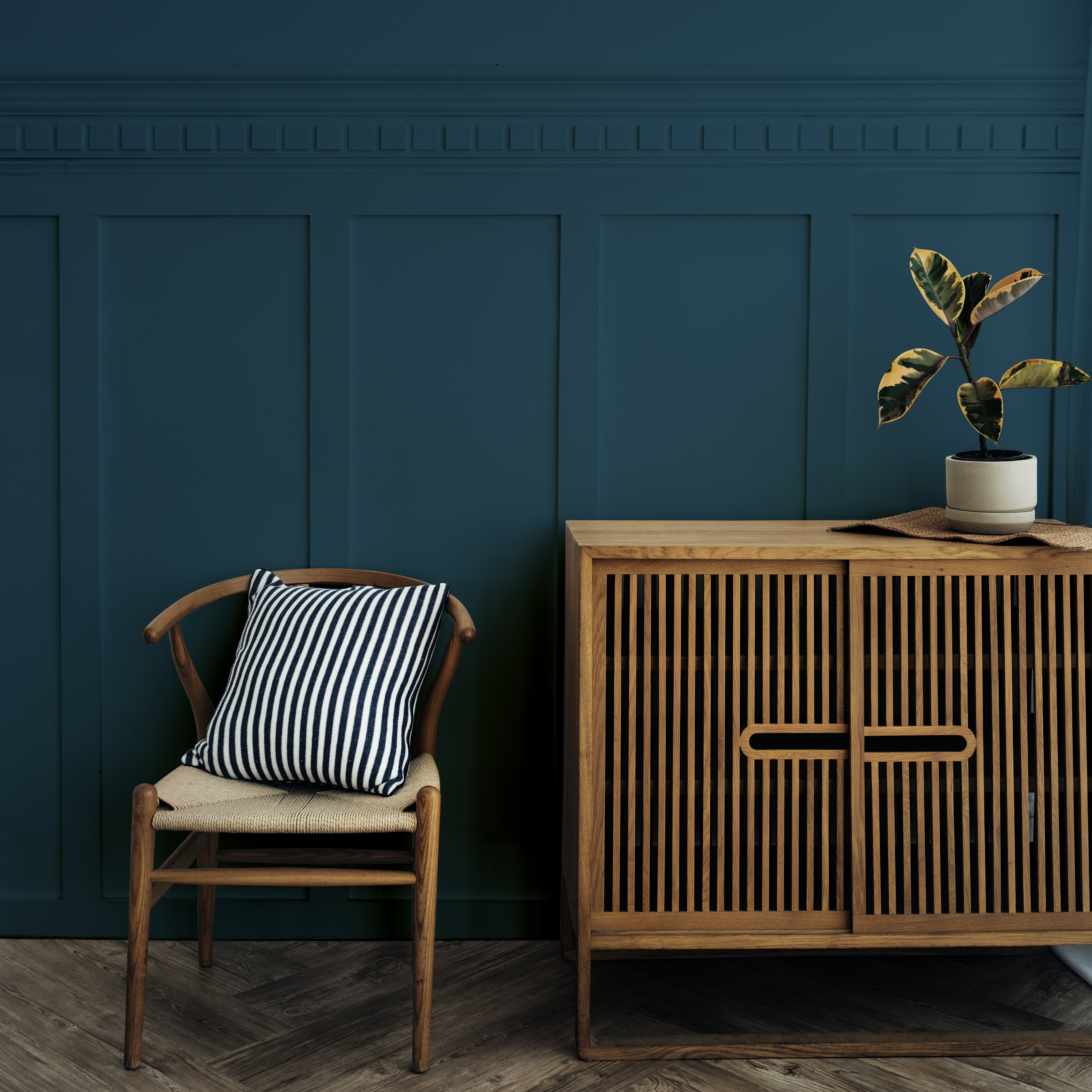 comment aménager un petit salon - Un meuble et une chaise en bois avec un mur peint en bleu foncé