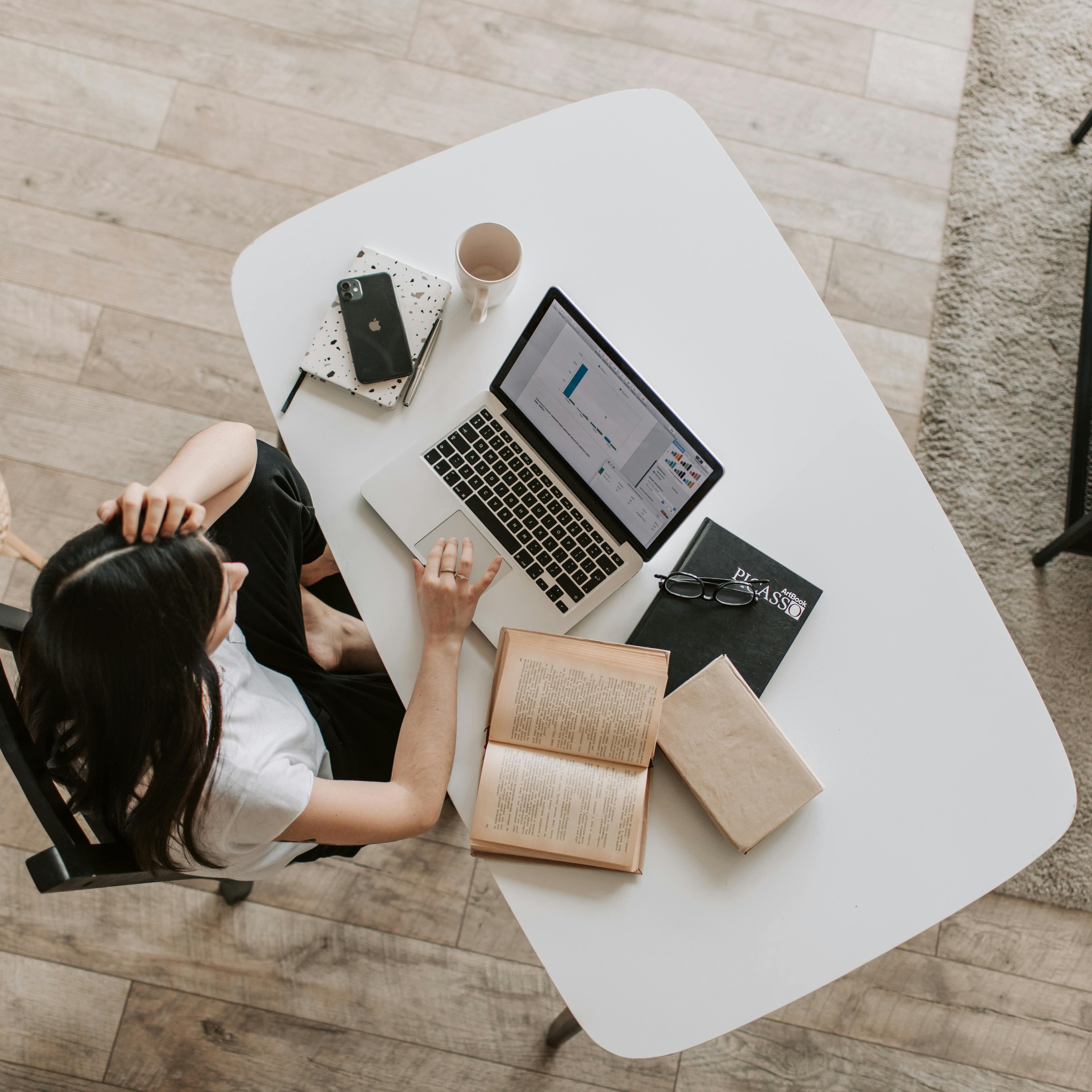 Aménager un coin bureau dans un salon – Une femme en train de travailler sur un grand bureau blanc aménagé dans le salon.