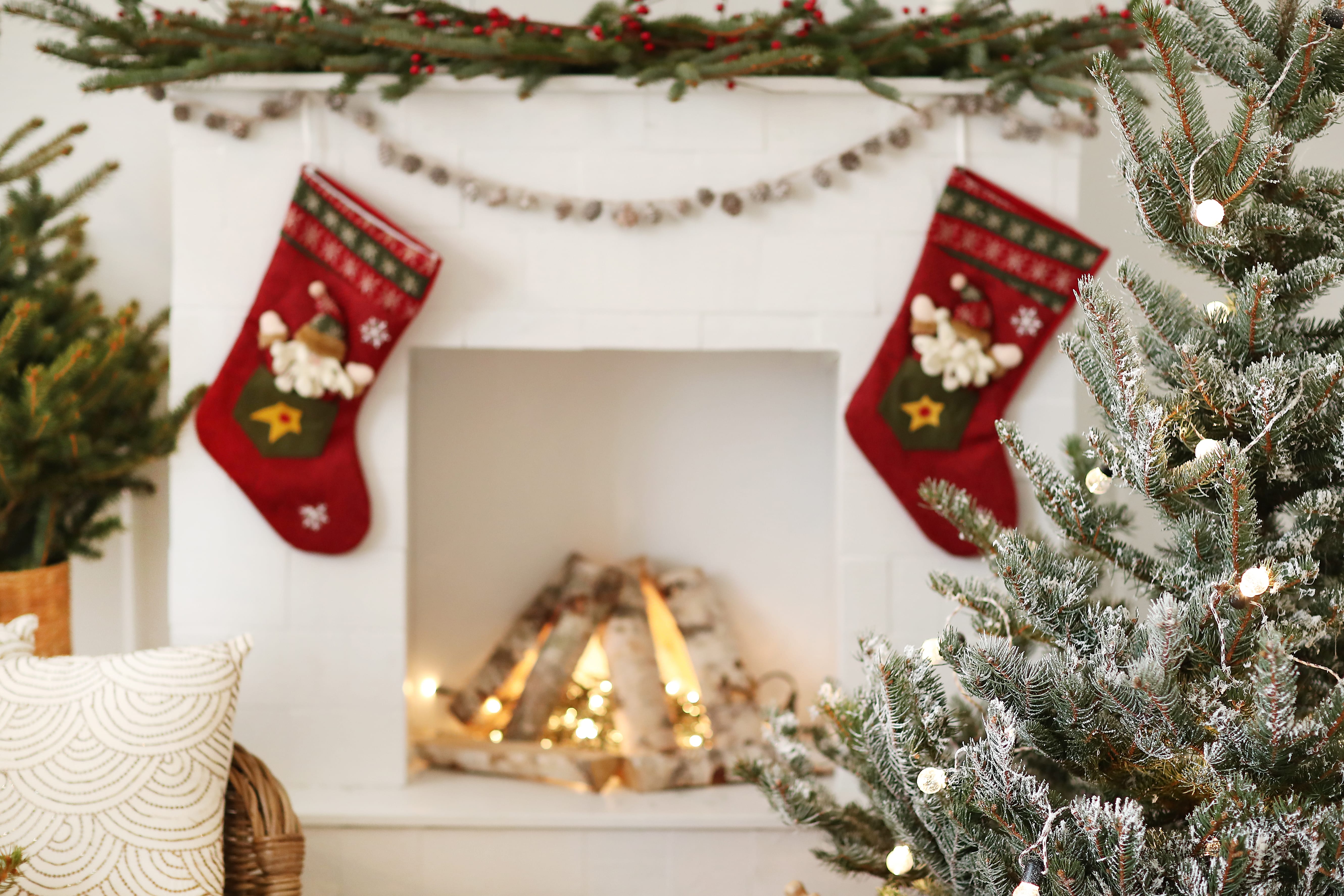 Comment décorer sa maison pour Noël - Une cheminée décorée pour Noël avec des chaussettes et une grande branche de sapin posée sur le manteau.